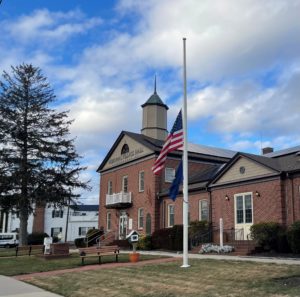 Photo of the front of Lindenhurst Village Hall with American flag at half-staff